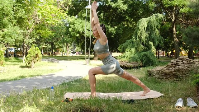 The girl is engaged in fitness, yoga, stretching on a mat in the park. 4k slow motion