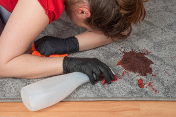  Woman crying in despair near dark stain, dirty spot on a carpeted floor, her hand with cleaning...