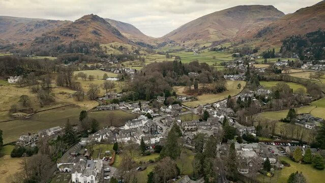 Rural Cumbrian countryside through captivating drone footage, capturing the small English town of Grasmere deep in the Lakeland fells, embraced by majestic mountains.
