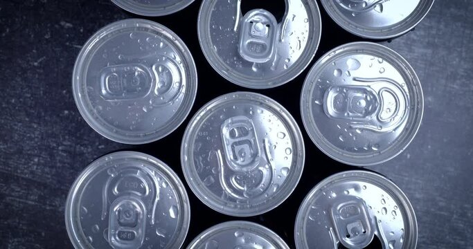 Cooled soda cans ready to drink on black background. Summer drink, thirsty, coke, juice consumption, recycle concept. Dolly shot 4k