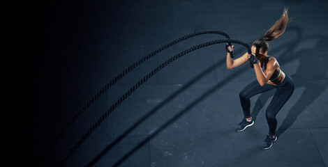 Effective Workout with a rope. Sportswoman trains in the functional training gym, performing...