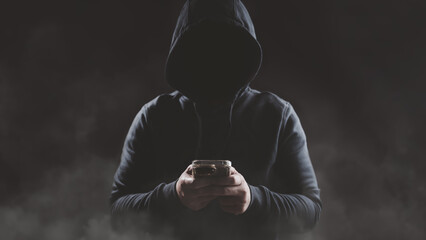 Hacker wear hood holding smartphone with red warning icon to launch ransomware malware attack on...