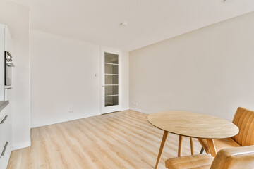 an empty living room with white walls and wood flooring, including a round dining table in the middle part of the room