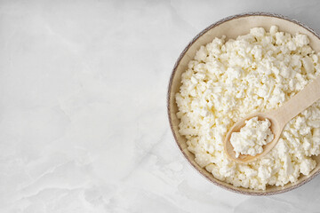 Bowl with tasty cottage cheese on light background