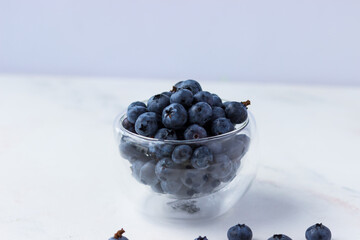 Blueberries in a transparent bowl on a white background. Summer berries