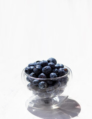 Blueberries in a transparent bowl on a white background. Summer berries
