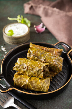 Delicious dolma - stuffed grape leaves with rice and meat on a dark stone background. Traditional Greek, Caucasian and Turkish cuisine.