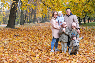 Fototapeta premium Large family posing in the autumn park. The family consists of mother, father and four children.