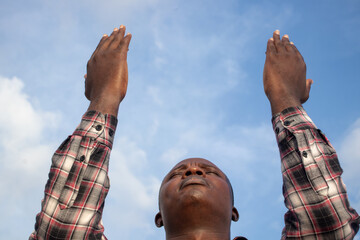 A preacher's unwavering devotion to the word of God, his hands stretched out to the blue sky as he...