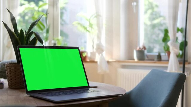 Laptop with a green screen is on a home desk.
