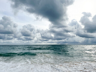 Empty Mai Khao beach in Thailand. Golden sand, deep blue water and moody monsoon clouds in the sky. Fantastic holiday destination. No people around. Wallpaper for inspiration and dreaming.