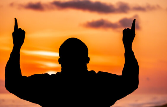 A moving image of a man's silhouette, standing out against the resplendent solstice sky, his hands stretched upwards in humble reverence to Jesus, expressing his unwavering faith.