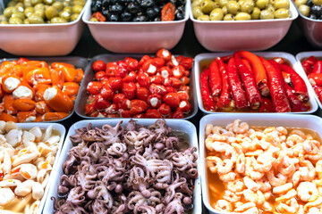 Section with marinated gourmet seafood, cheese-stuffed peppers and green and black olives at the farmers market