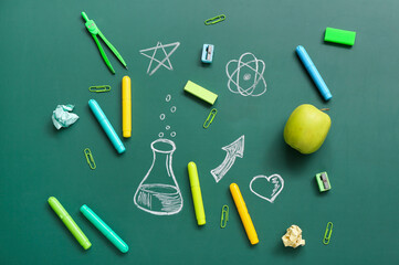 Different stationery with drawings on green chalkboard