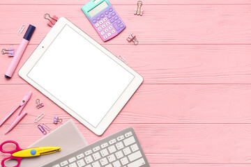 Tablet with calculator and different stationery on pink wooden background