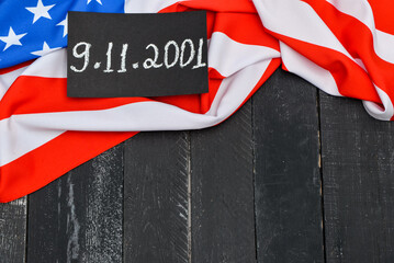 Fototapeta na wymiar USA flag and card with date of National Day of Prayer and Remembrance for the Victims of the Terrorist Attacks on black wooden background