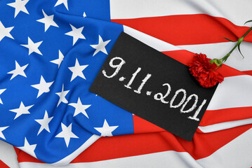 Fototapeta na wymiar Carnation flower and card with date of National Day of Prayer and Remembrance for the Victims of the Terrorist Attacks on USA flag