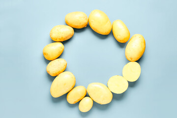 Frame made of raw potatoes on blue background