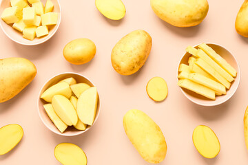 Bowls with cut and whole potatoes on pink background