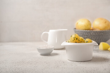 Bowl with boiled baby potatoes on light background