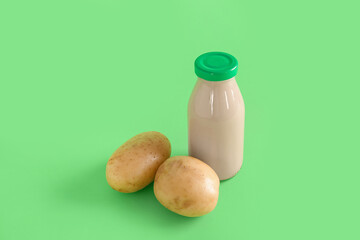 Bottle of tasty potato milk on green background