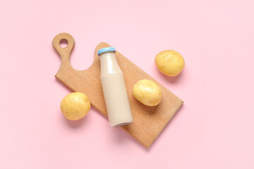 Bottle of tasty potato milk on pink background