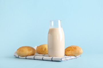 Bottle of tasty potato milk on blue background