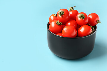 Bowl with fresh cherry tomatoes on blue background