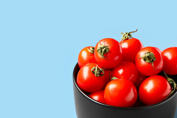 Bowl with fresh cherry tomatoes on blue background