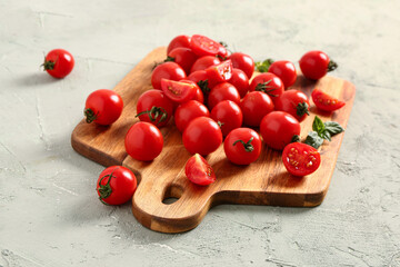 Wooden board with fresh cherry tomatoes on grey table