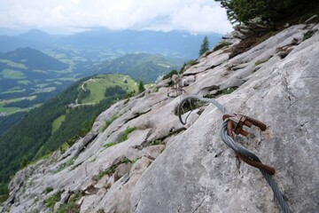 Close up of metal rope insurance on rocks on tourist trail in mountains. Summer mountains views during hiking from Gosau Valley to Donnerkogel peak in Austrian Alps