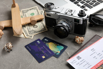 Credit cards, money, photo camera and wooden plane on grunge background, closeup