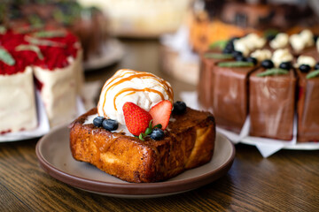 A ice Cream with fresh fruits on the toast topped with caramel on brown plate with cake background
