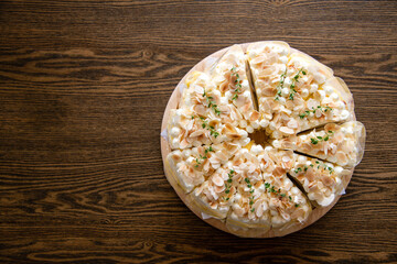 top view of white chocolate cakes topped with macadamia slices on wooden background