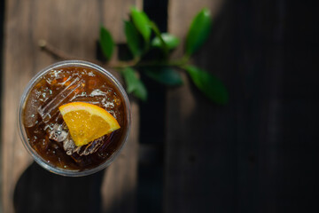 a glass of mix coffee with orange sliced on top on wooden table