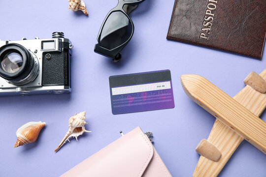 Composition with credit card, passport, wooden plane and photo camera on lilac background