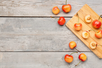 Naklejka na ściany i meble Board with sweet yellow cherries on grey wooden background