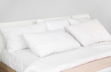 Fototapeta na wymiar Large double bed with white pillows in interior of light bedroom