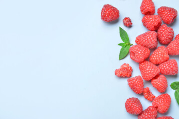 Many fresh raspberries and mint on blue background