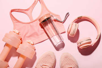 Composition with bottle of water, headphones, sports bra and dumbbells on color background