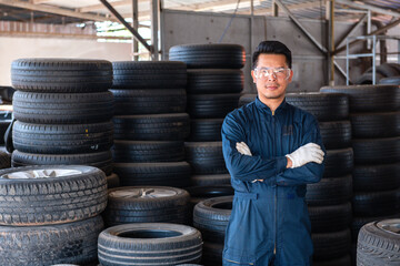 A mechanic man standing in front of the tires holding his arm together