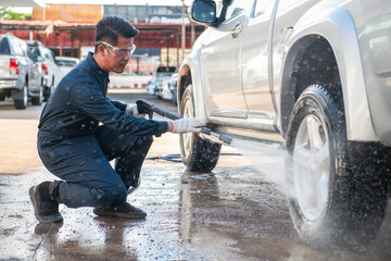 A mechanic man cleaning car with high pressure washer