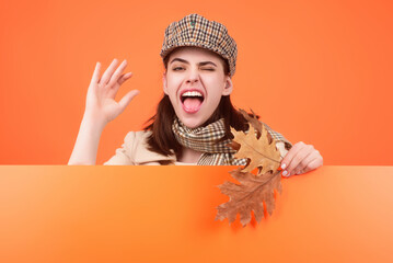 Fashionable hipster woman in trendy autumn fall outfit, stylish hat. Beautiful girl hold autumn maple leaves, isolated on studio background. Portrait of autumnal woman with maple leaf.