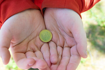 Hand holding euro coins on the street.
