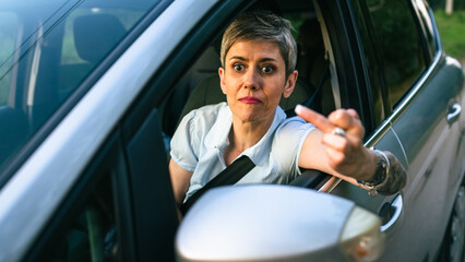woman senior mature driver show middle finger trough the window of car
