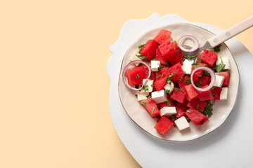 Plate of tasty watermelon salad on yellow background