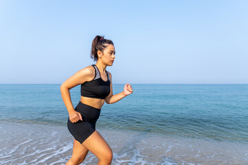latin woman in sportswear on the beach, running on the seashore