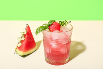 Glass of tasty watermelon cocktail on white table near green wall