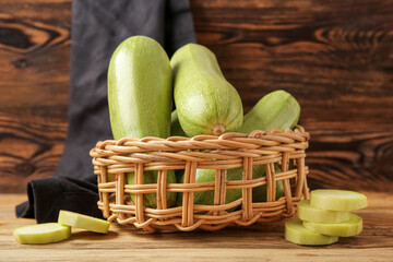 Wicker bowl with fresh green zucchini on wooden background