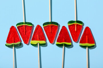 Lollipops in shape of watermelon slice on blue background